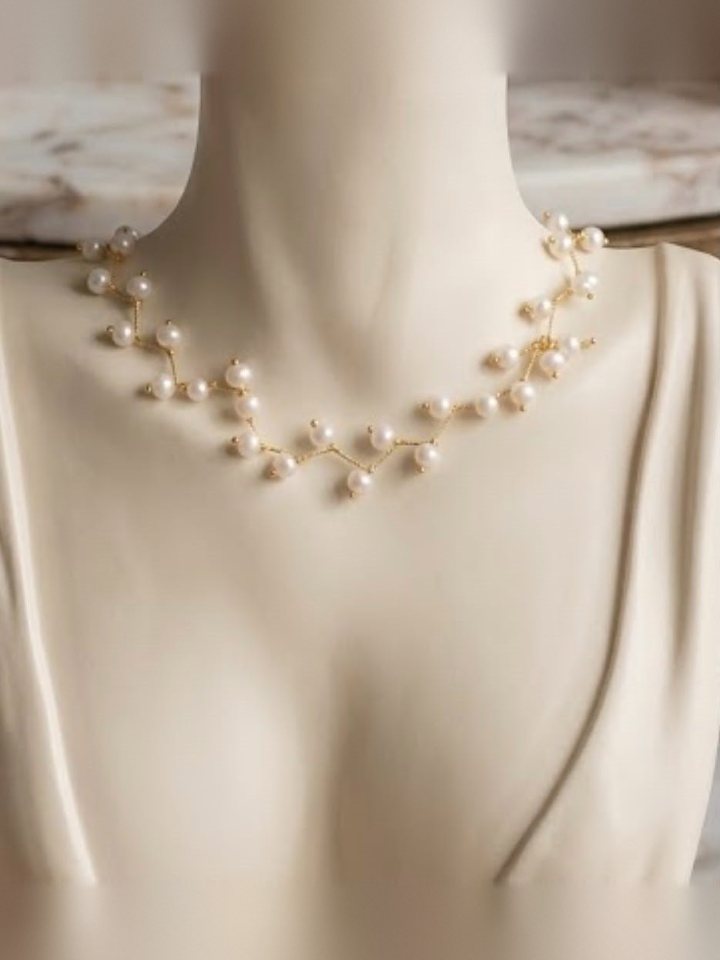 A zigzag strand of white pearls worn at the collarbone